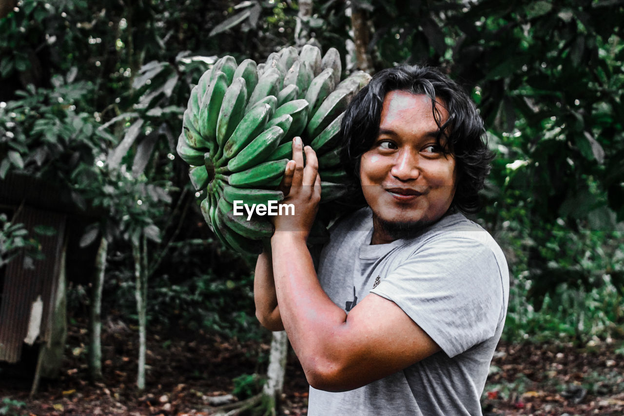 Portrait of smiling man standing against plants