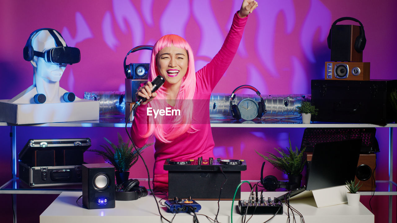 music, technology, dj, arts culture and entertainment, adult, one person, women, indoors, performance, headphones, young adult, stage, happiness, emotion, event, enjoyment, communication, microphone, listening, occupation, singing, waist up, arm, purple, cheerful, fun, night, input device, smiling, musician