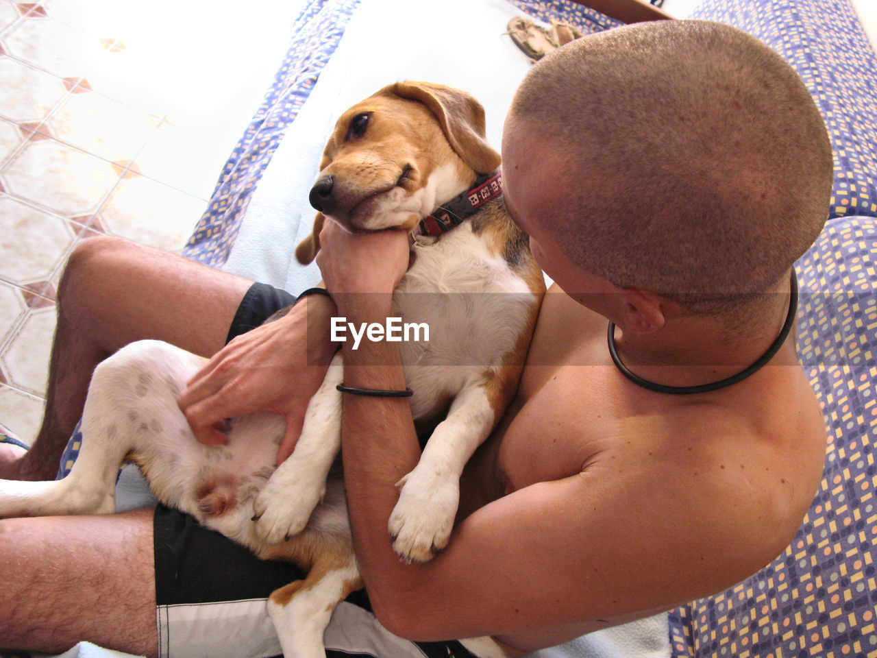 High angle view of shirtless man holding dog at home