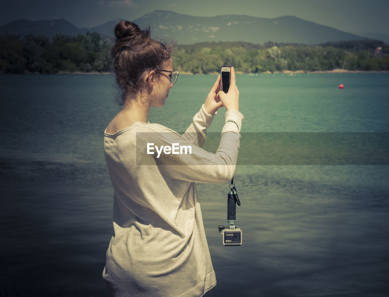 WOMAN PHOTOGRAPHING AT LAKE