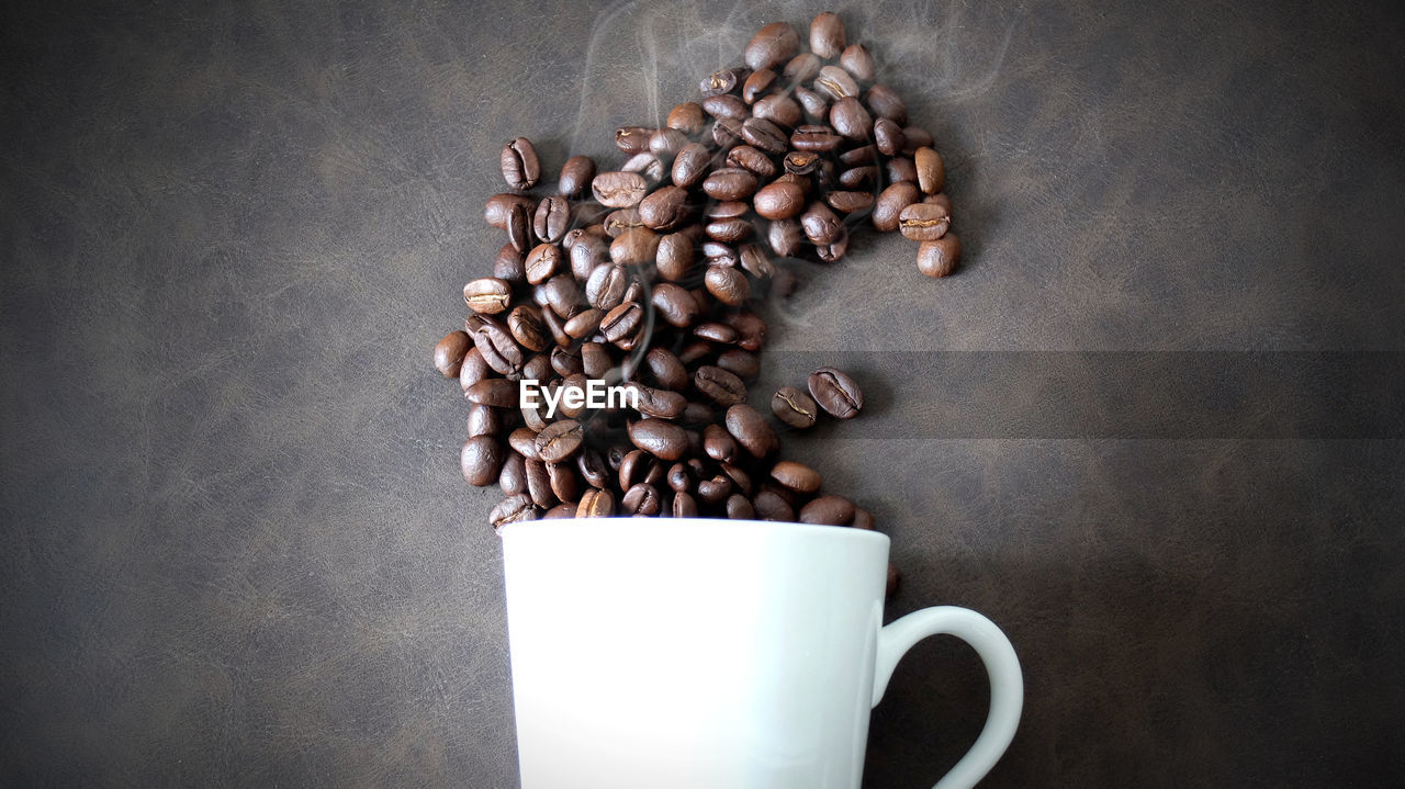 HIGH ANGLE VIEW OF COFFEE CUP ON TABLE AGAINST WALL