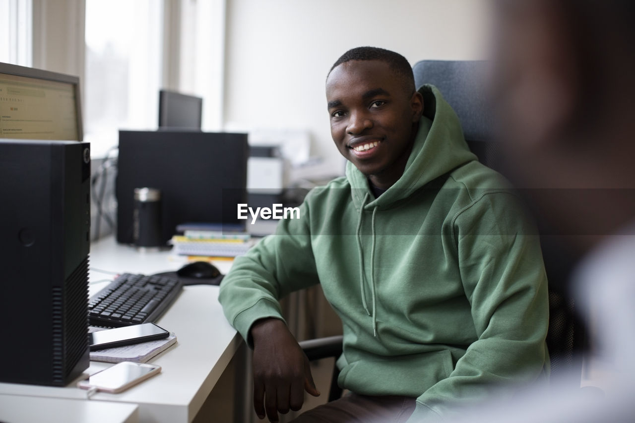 Portrait of smiling male trainee sitting at desk in office