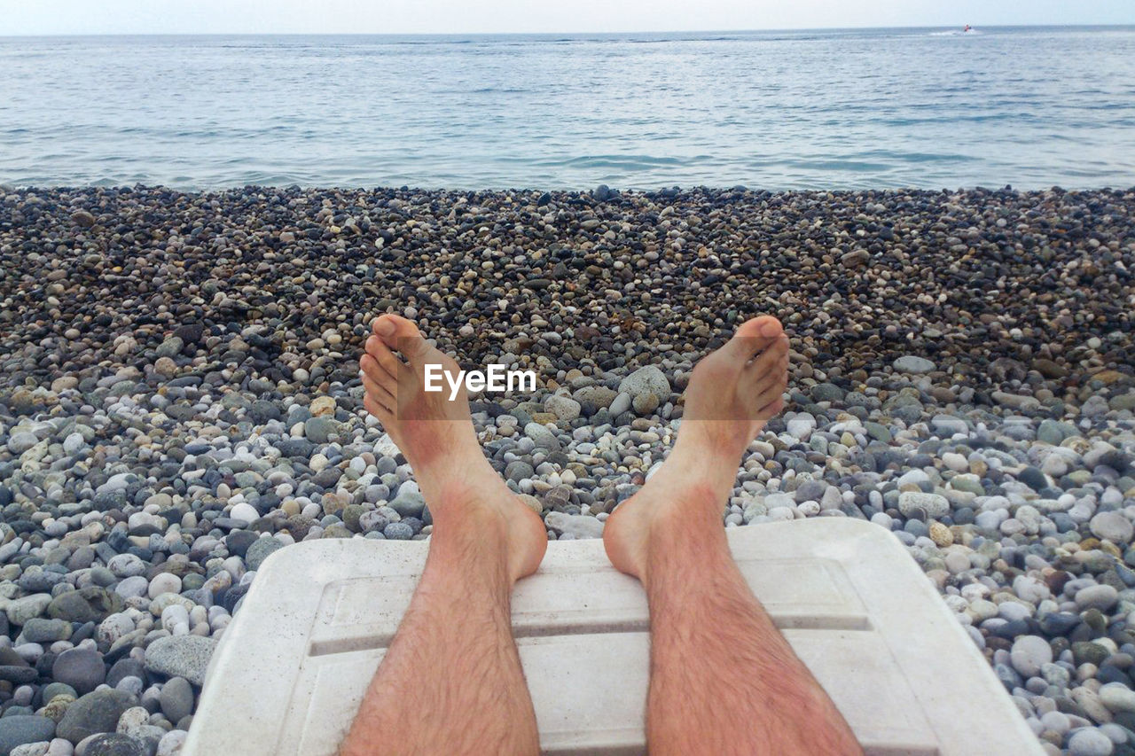 Men's hairy legs on the beach by the sea