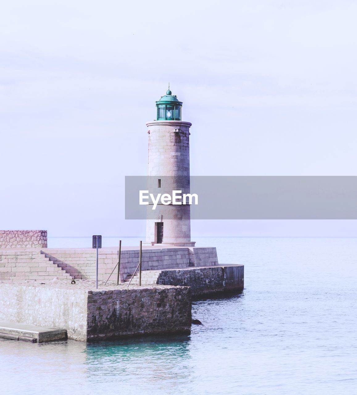 Lighthouse on building by sea against sky