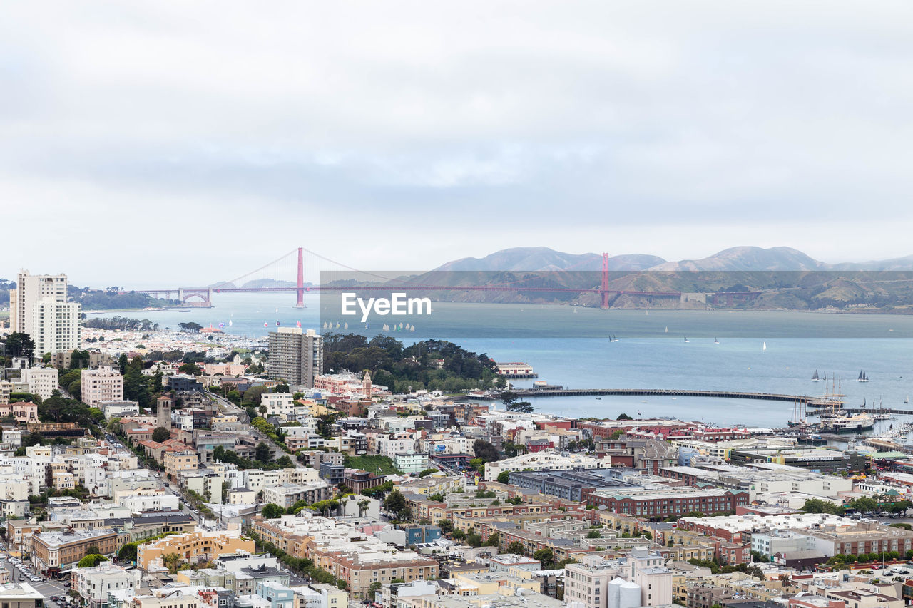 HIGH ANGLE VIEW OF BRIDGE OVER SEA AND BUILDINGS IN CITY