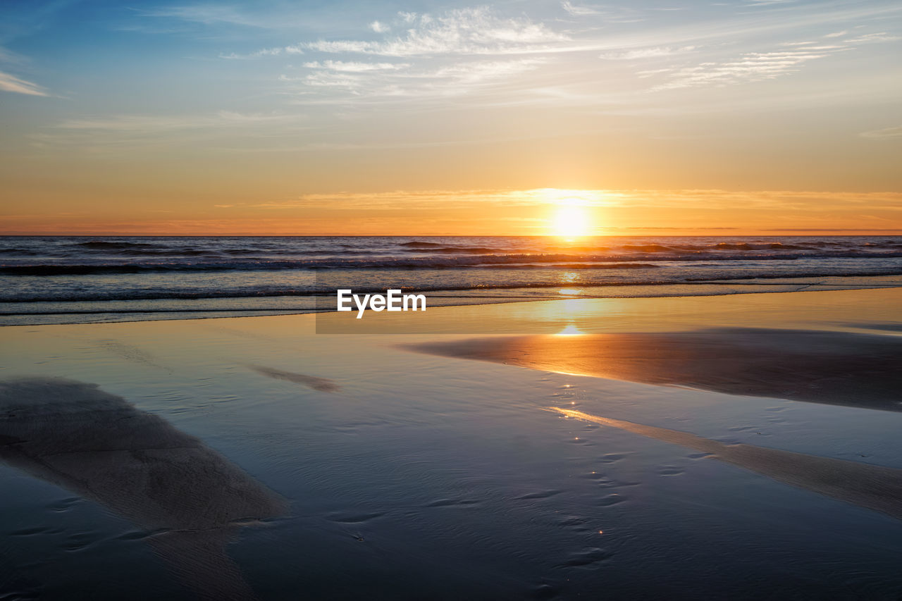 sky, water, sea, sunset, beauty in nature, beach, scenics - nature, land, nature, tranquility, tranquil scene, reflection, horizon, horizon over water, ocean, cloud, sunlight, sun, coast, shore, dawn, idyllic, no people, wave, sand, outdoors, orange color, dramatic sky, environment, body of water, travel destinations, seascape, landscape, travel