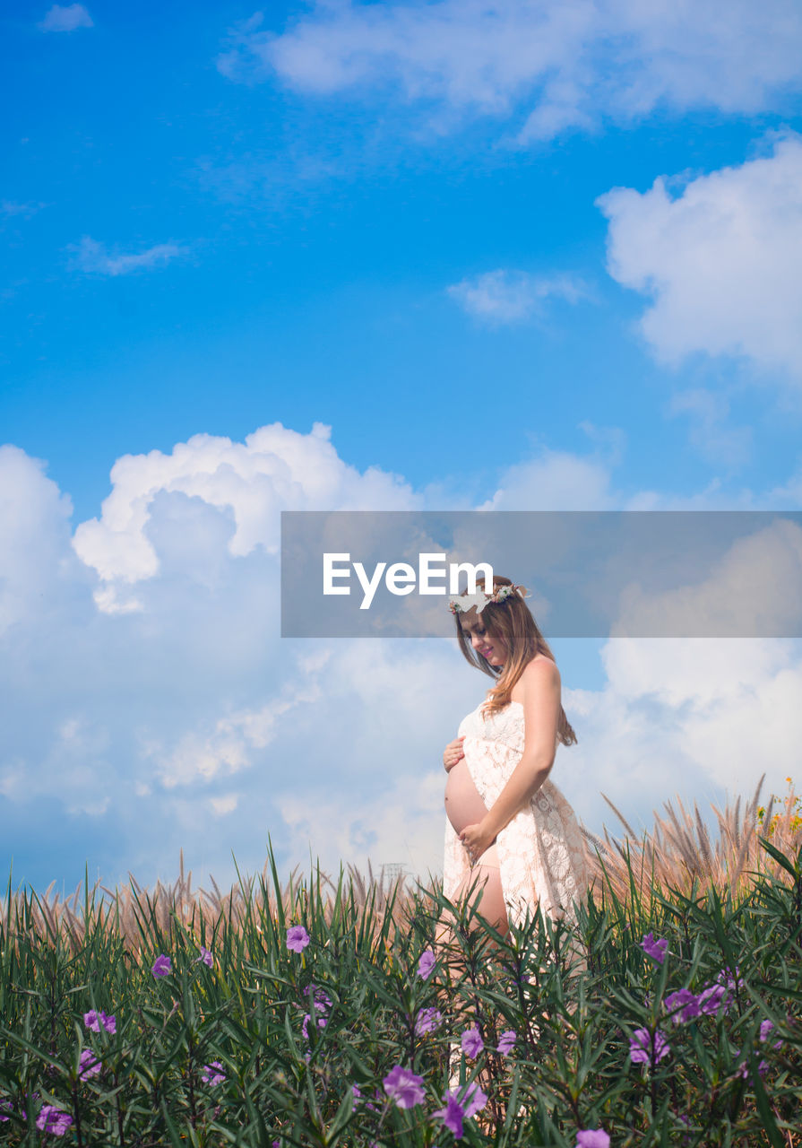 Pregnant woman standing on field against sky