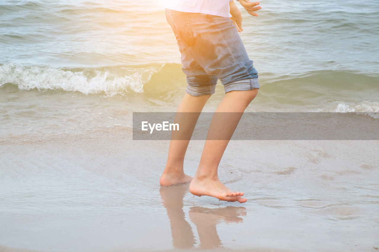 Low section of man standing at beach