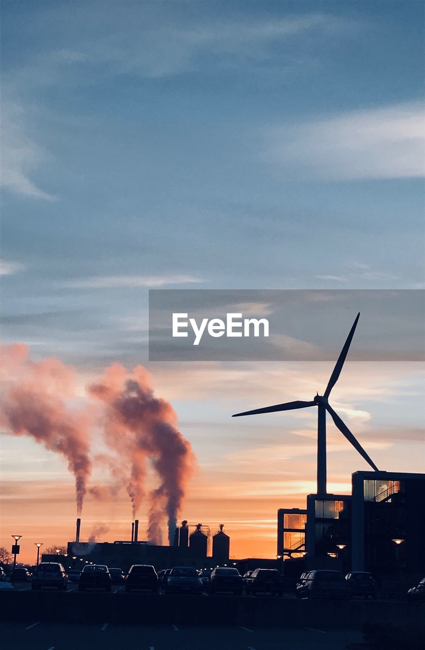 Smoke emitting from chimneys against sky during sunset