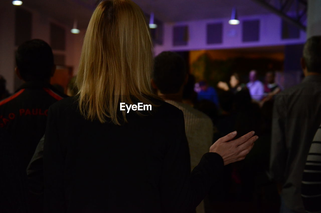 REAR VIEW OF TWO PEOPLE STANDING IN THE DARK