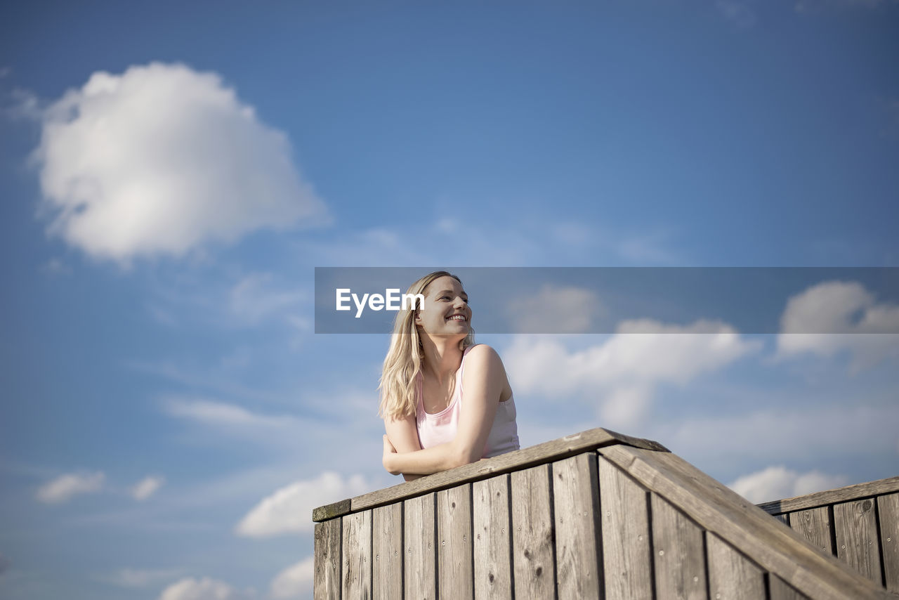 Low angle view of beautiful woman standing against sky