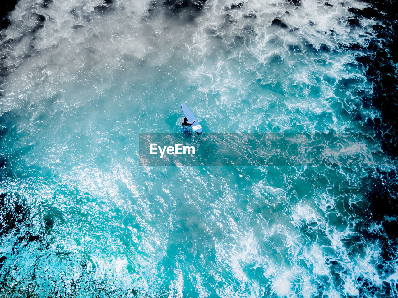 HIGH ANGLE VIEW OF PEOPLE SURFING IN SEA