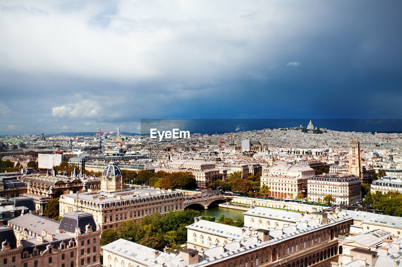 HIGH ANGLE VIEW OF BUILDINGS AGAINST CLOUDY SKY