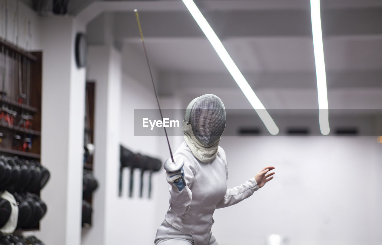 Woman in fencing outfit practicing at gym