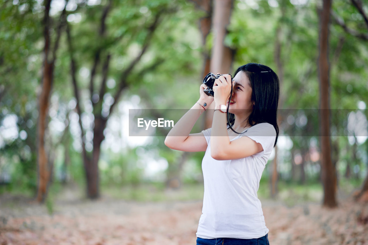 The young female photographer is happy with photography and his little camera in the natural corner