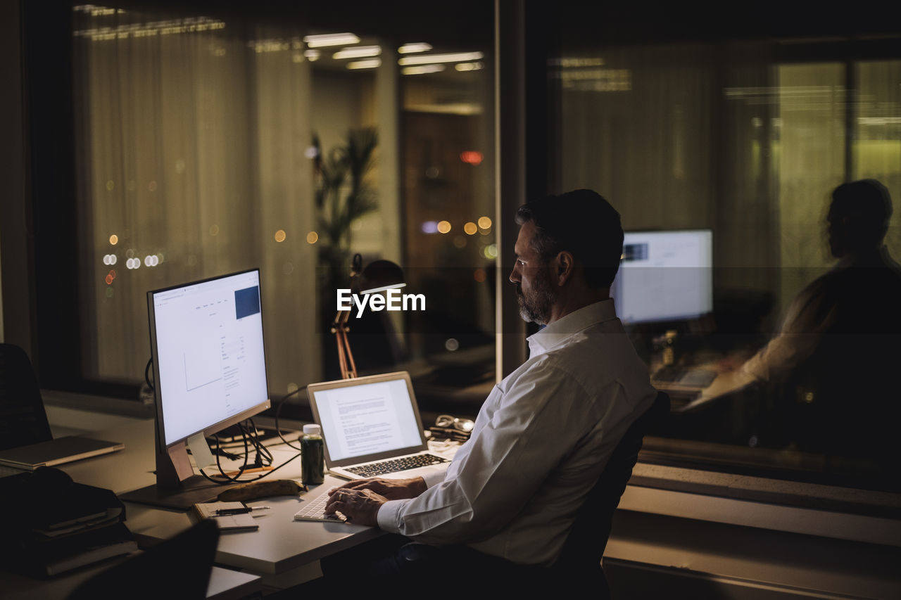 Businessman typing on computer keyboard while working in office at night