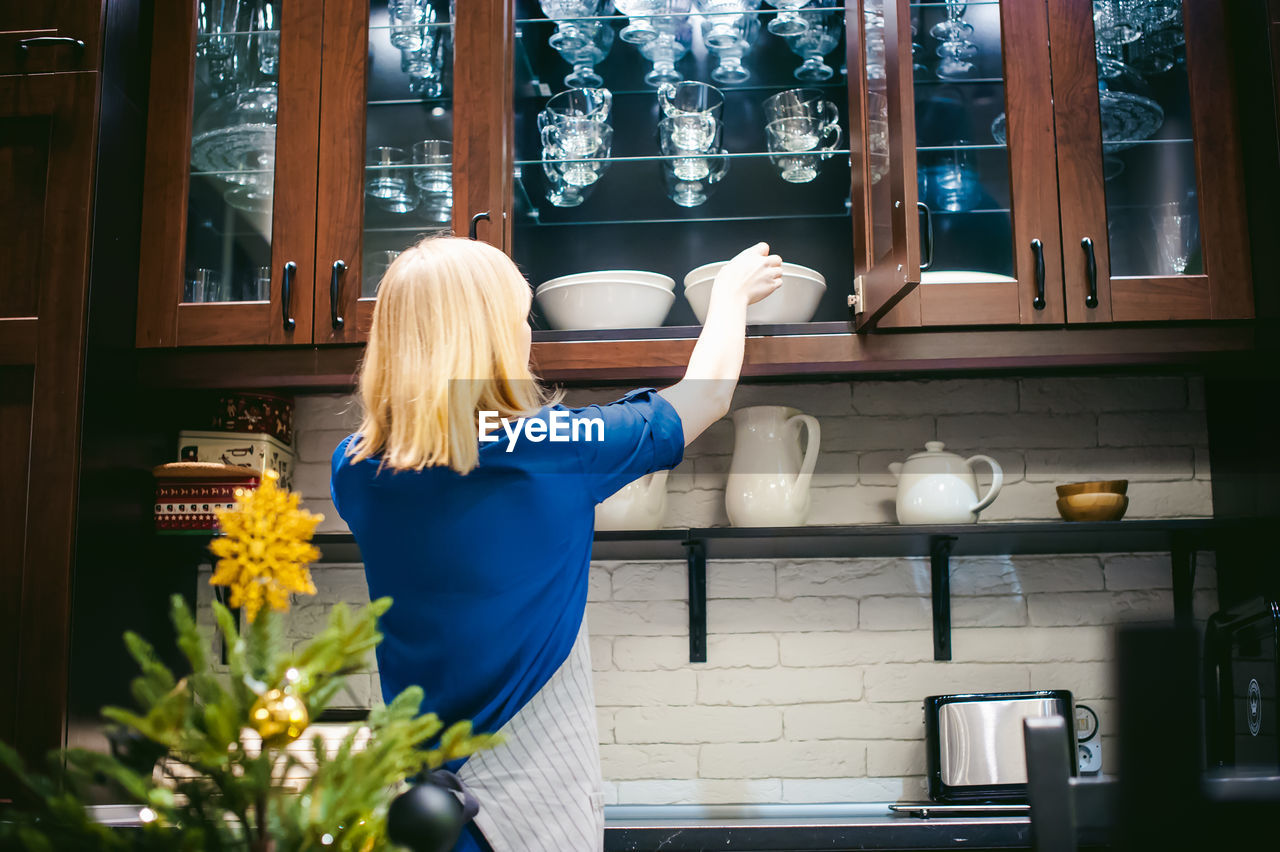 Woman taking bowl from kitchen cabinet