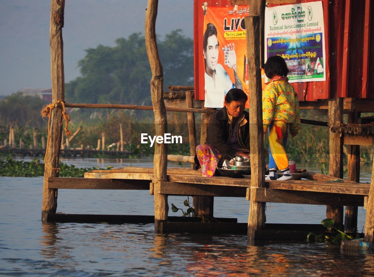 PEOPLE LOOKING AT LAKE AGAINST BUILT STRUCTURE IN WATER