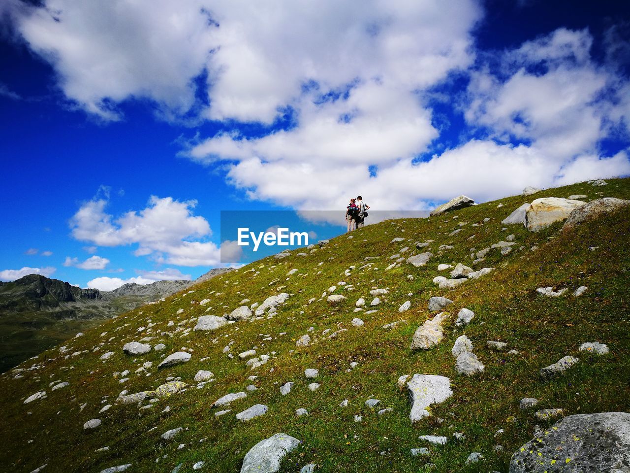 Low angle view of friends standing on hill against cloudy sky