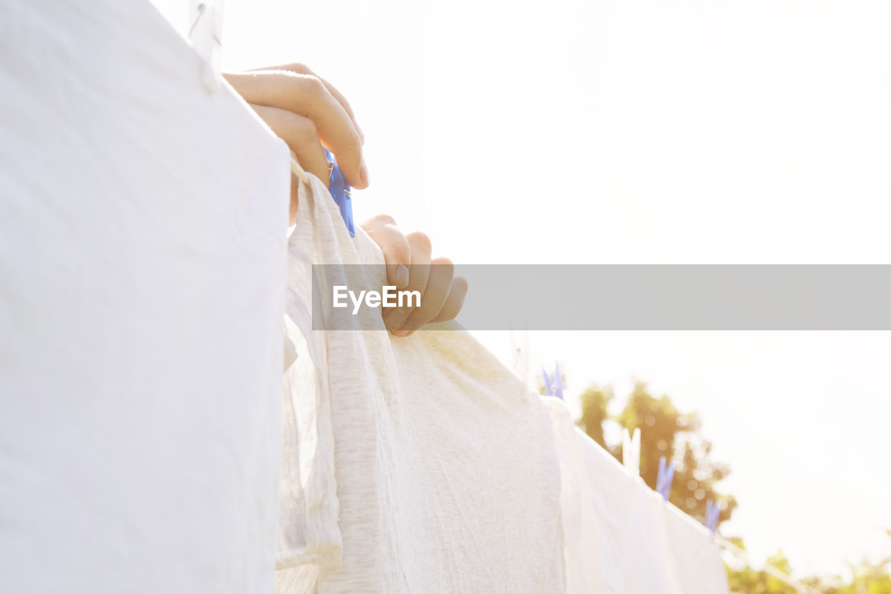 Close-up of woman holding white umbrella against sky