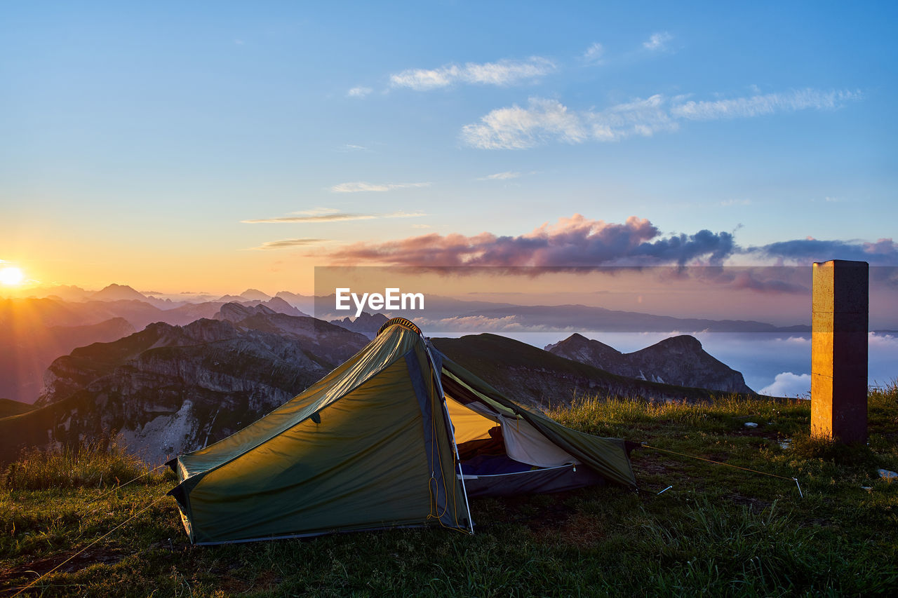 TENT ON FIELD AGAINST SKY AT SUNSET