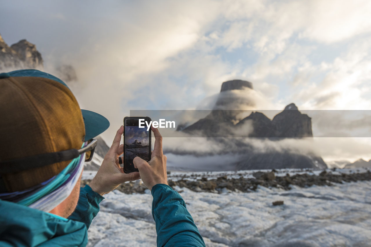Man uses smartphone to take a photo of mount asgard.