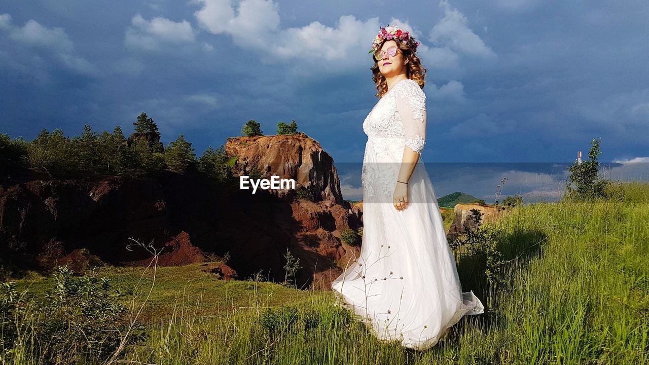 Woman in dress standing on field against sky