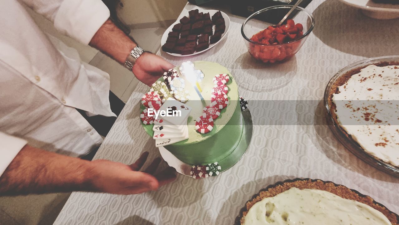 food and drink, food, baked, dessert, hand, freshness, adult, sweet food, one person, table, high angle view, indoors, sweet, cake, lifestyles, holding, healthy eating, preparing food, men, women, icing, midsection, fruit, meal, bowl