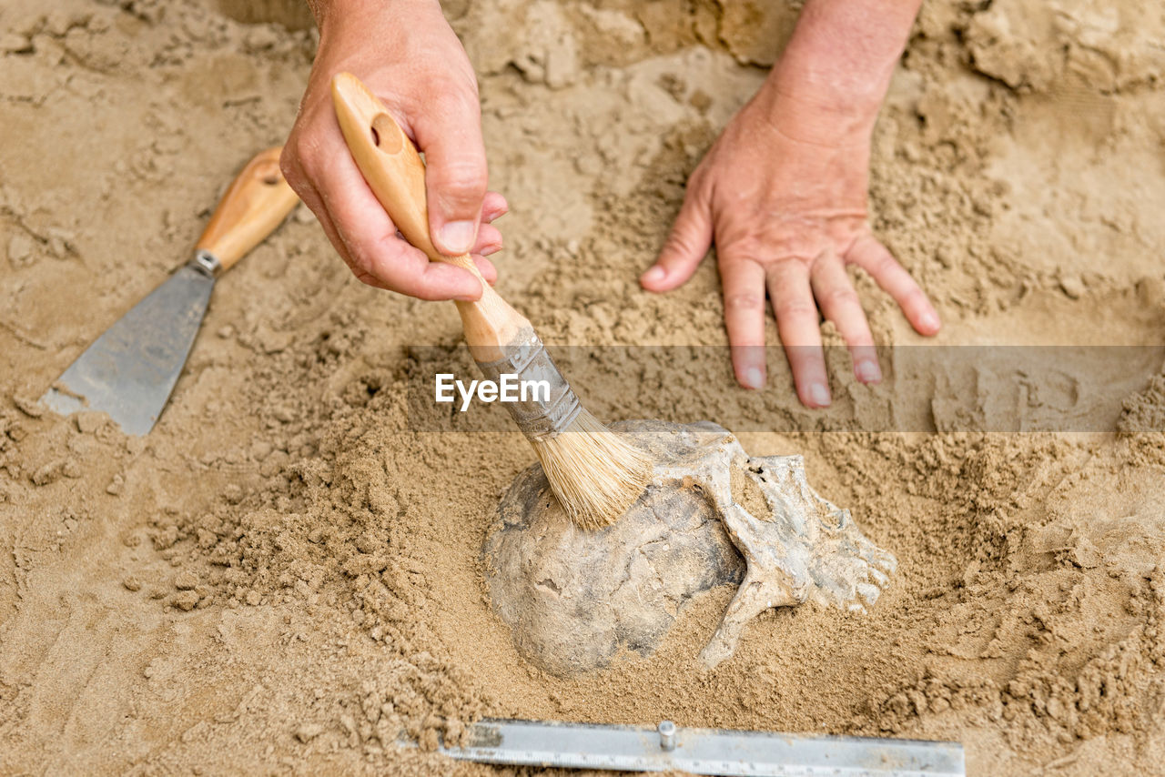 Close-up of hands working on sand