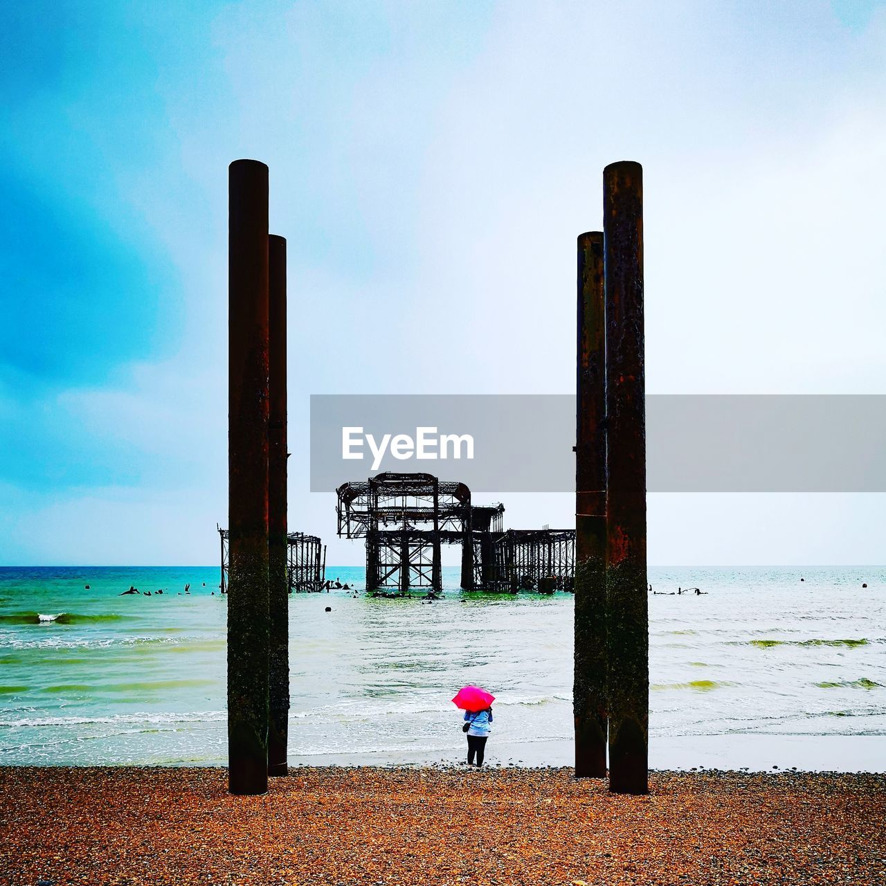 REAR VIEW OF BOY ON BEACH AGAINST SKY