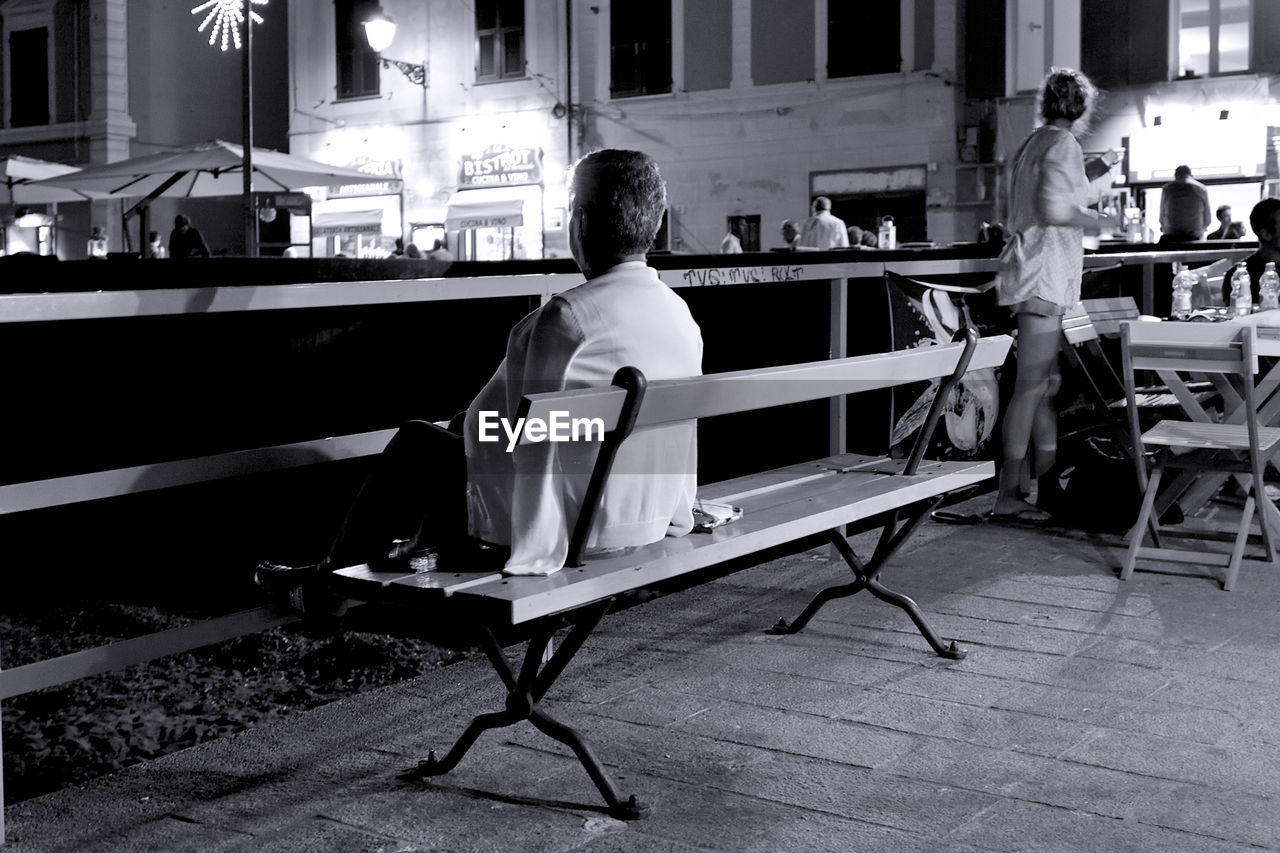 REAR VIEW OF PEOPLE SITTING ON CHAIR