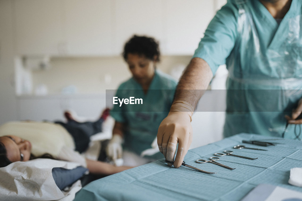 Male surgeon arranging surgical equipment on table in hospital