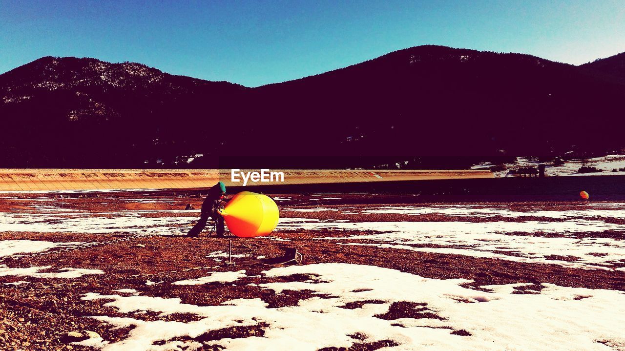 Man carrying yellow buoy on field during winter