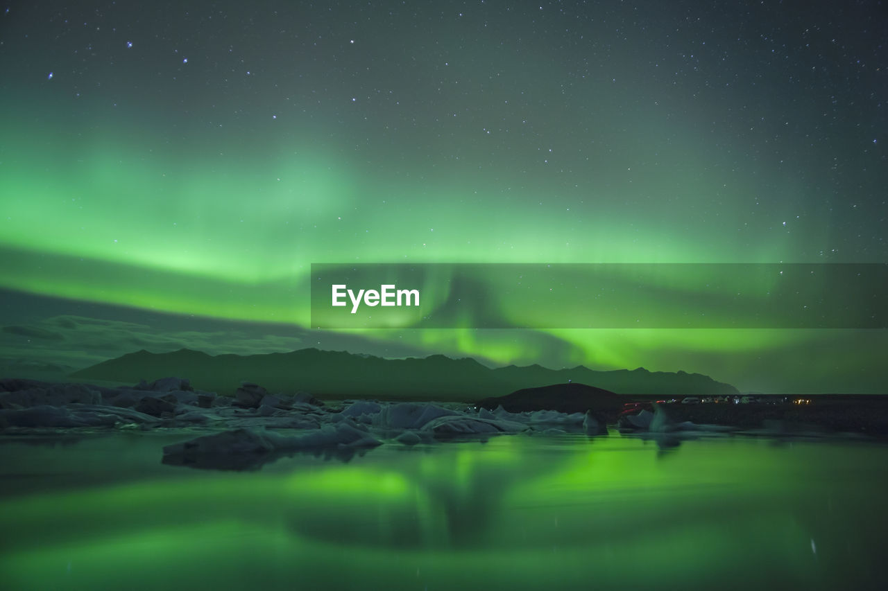 Scenic view of aurora borealis over lake against sky at night