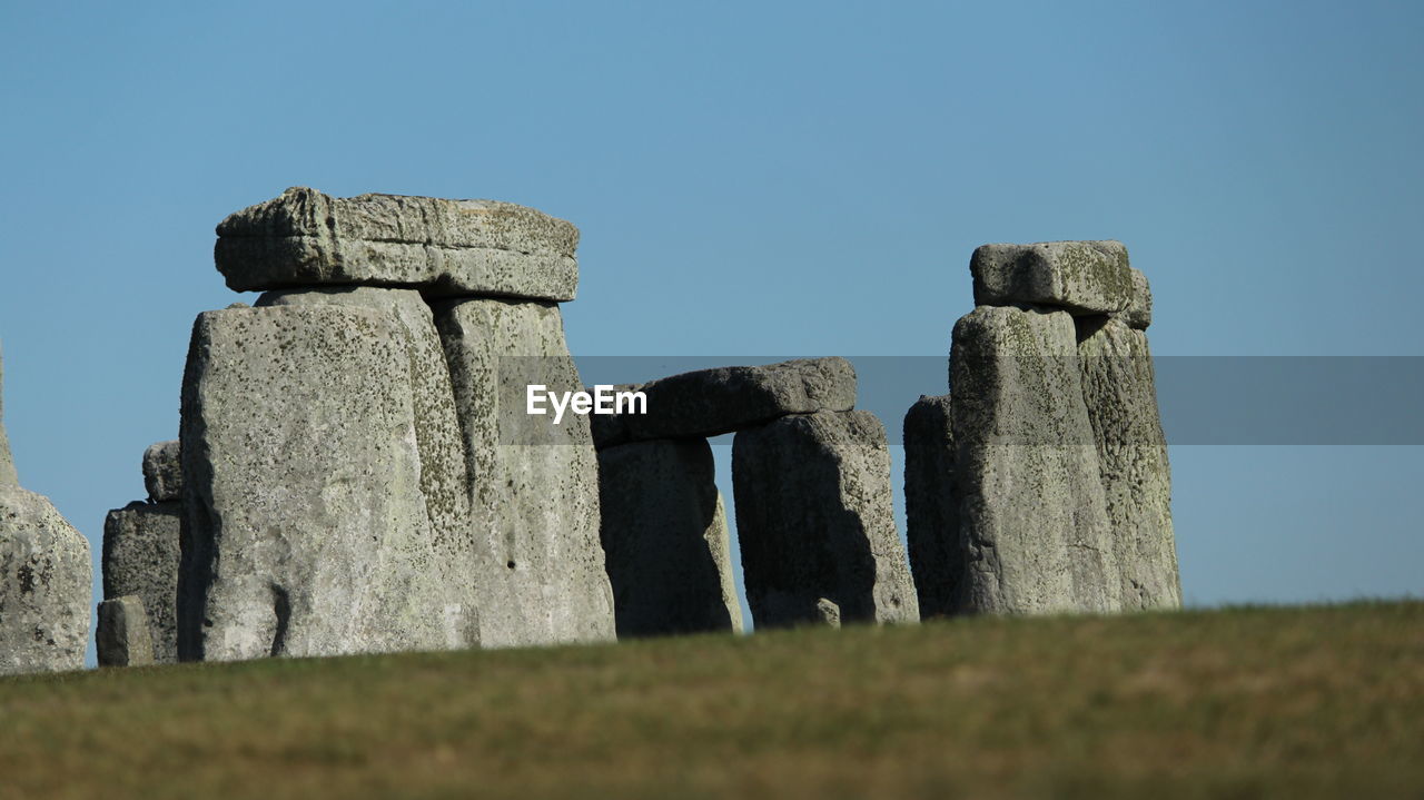 Low angle view of stone structure on field against clear sky