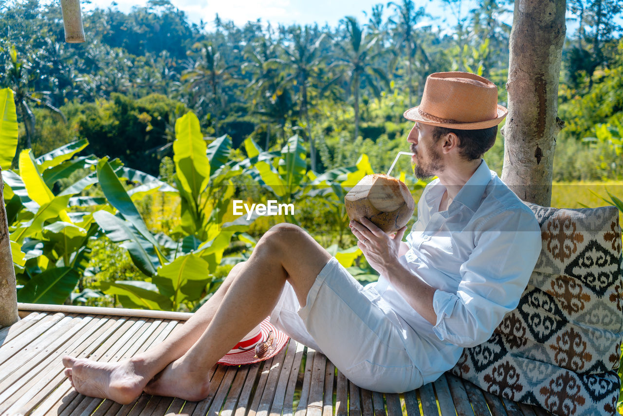 Man relaxing in his tropical vacation sitting in gazebo by the jungle