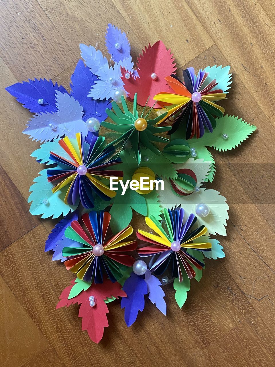 multi colored, wheel, origami paper, origami, high angle view, flower, indoors, table, creativity, art, no people, art paper, craft, petal, wood, still life, directly above, paper, blue, close-up, decoration, variation, large group of objects