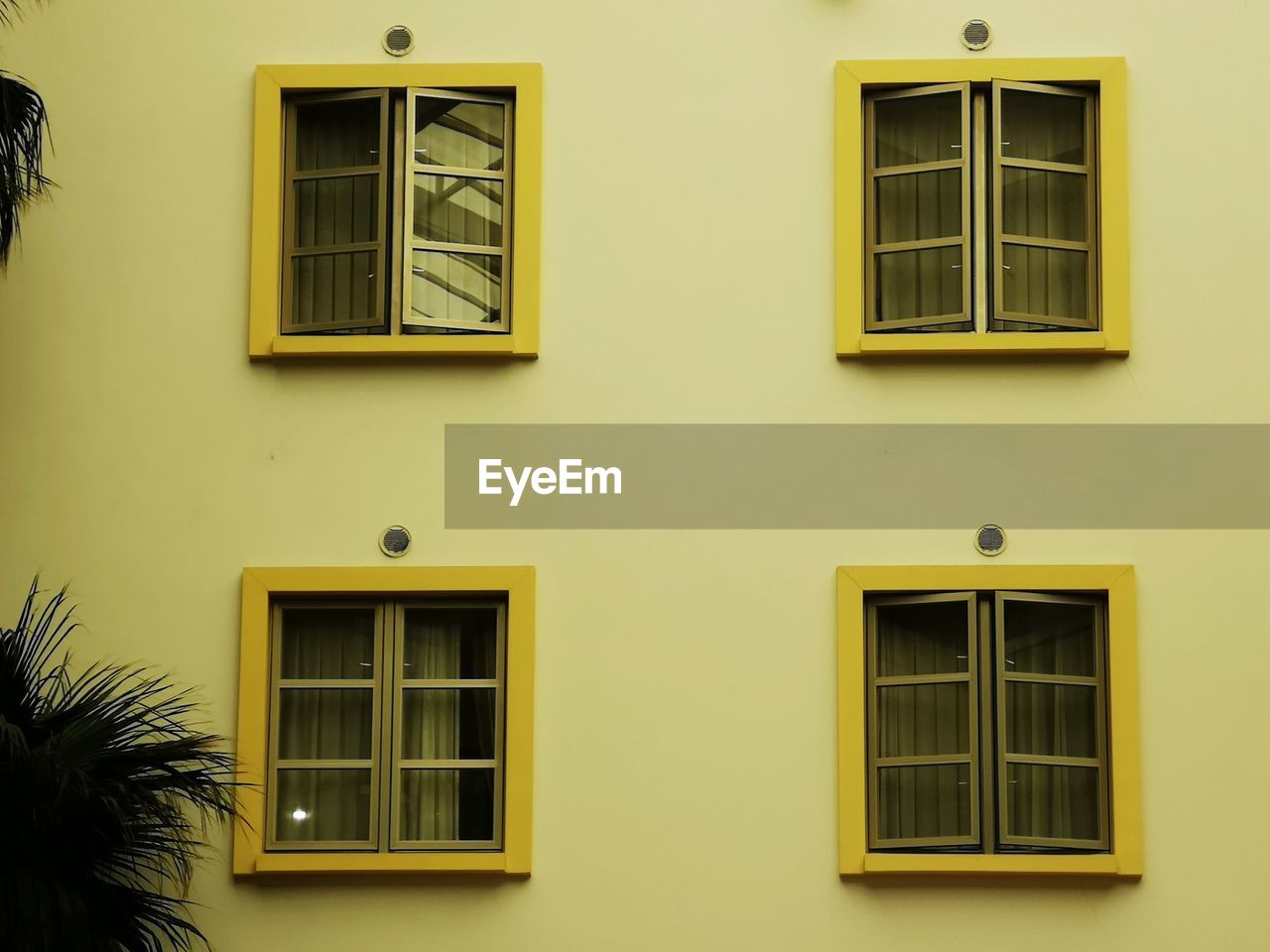 LOW ANGLE VIEW OF YELLOW HOUSE WINDOW ON BUILDING