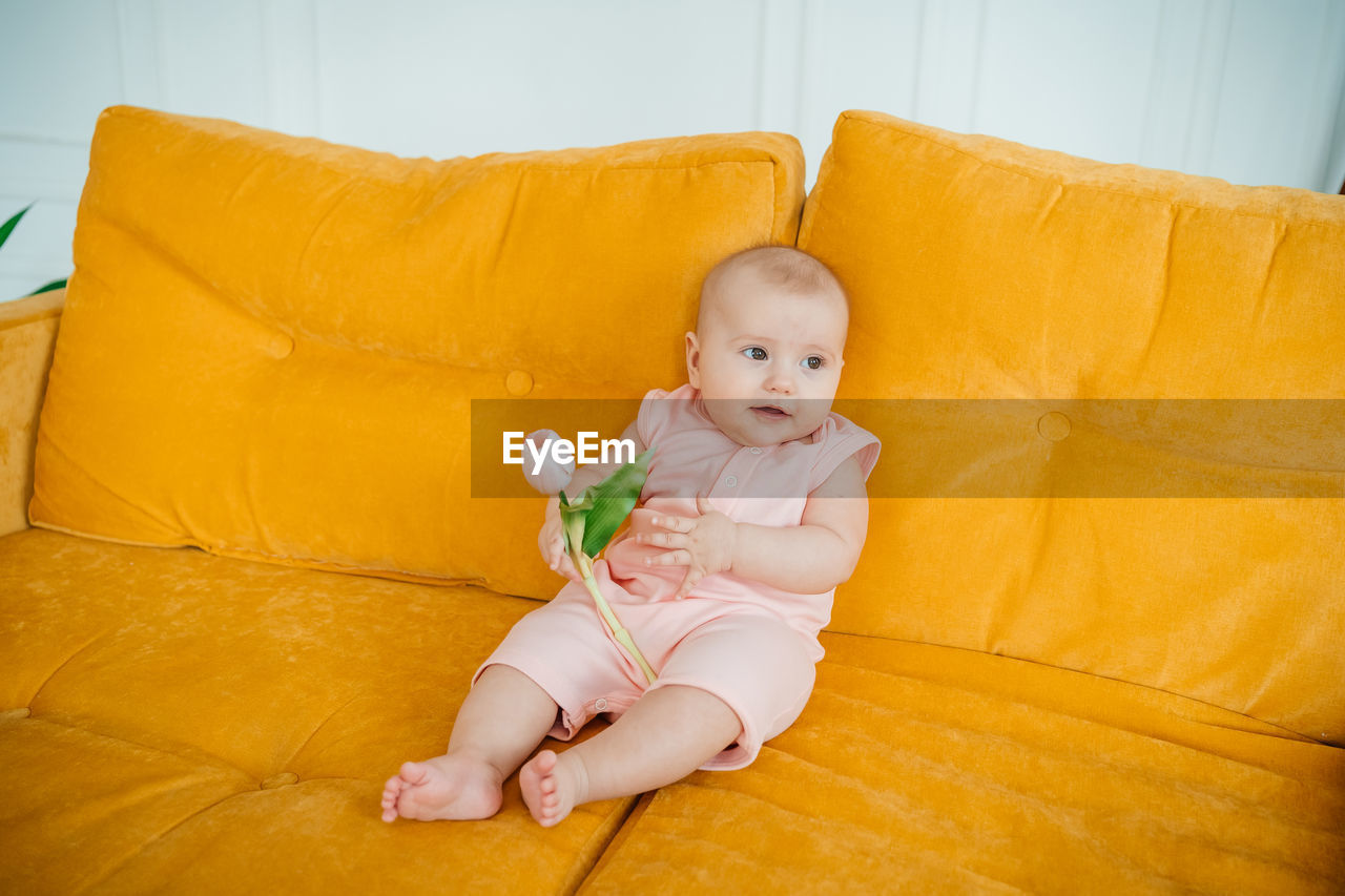 Child on a yellow sofa with flowers at home