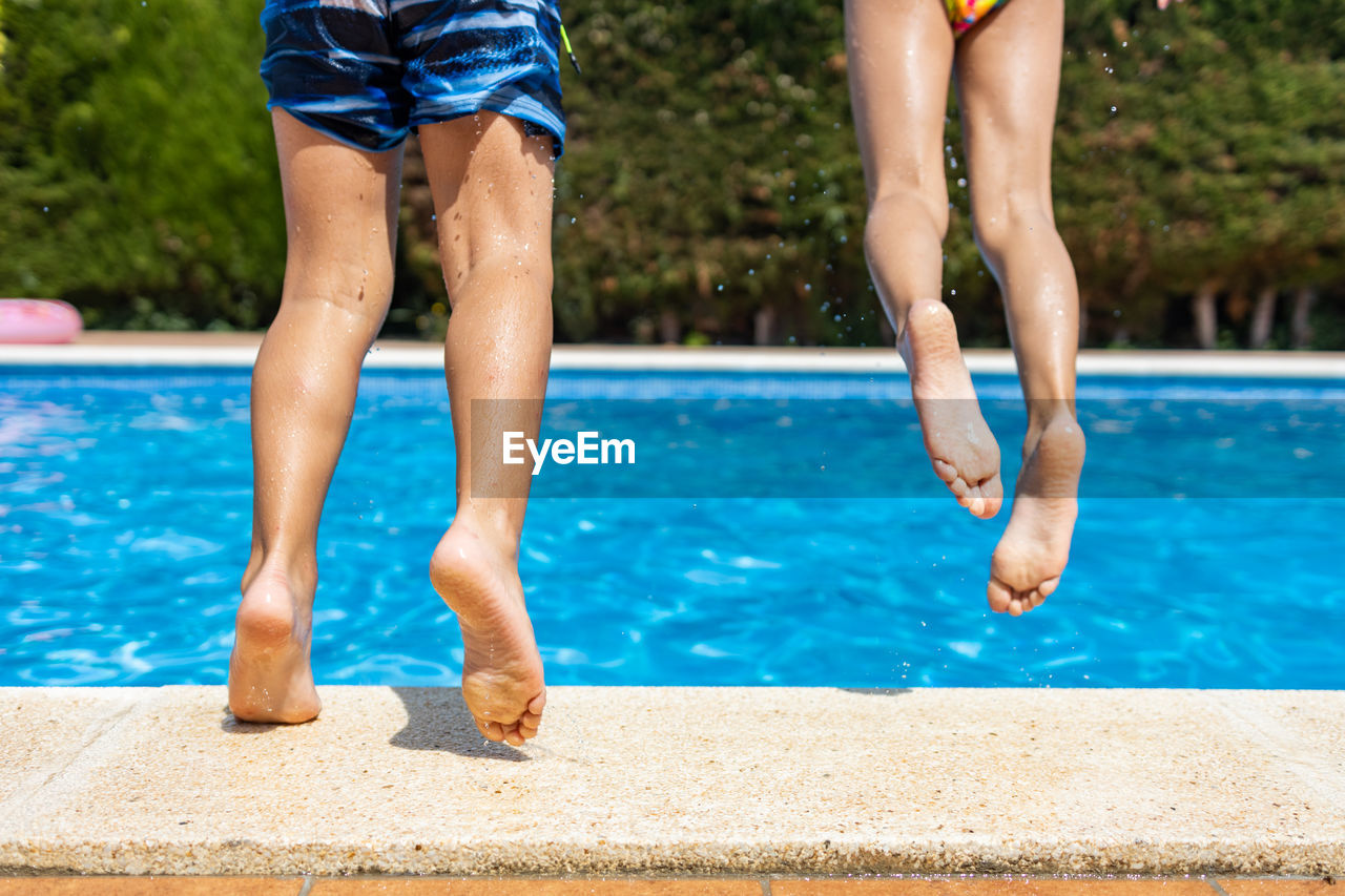 Two little kids jumping into a swimming pool. leg detail