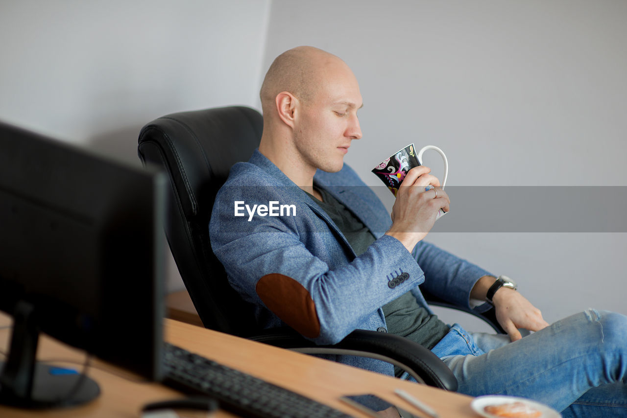 Businessman having coffee at desk in office