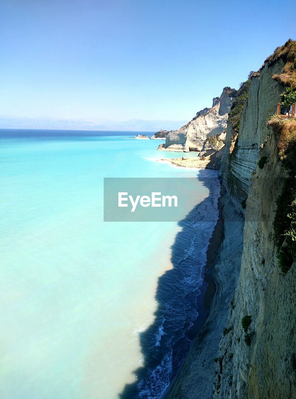 Scenic view of cliff by sea against sky