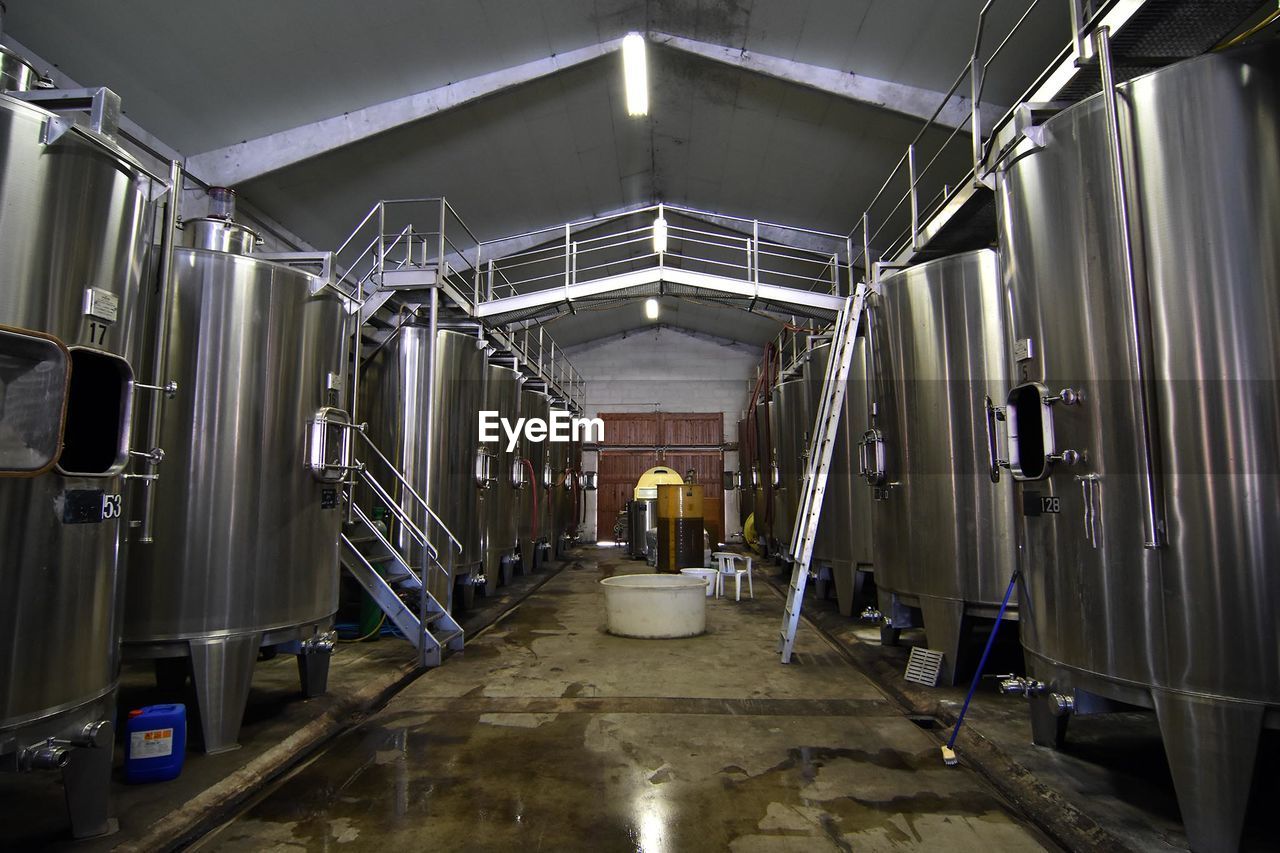Aisle amidst metallic storage tanks at winery