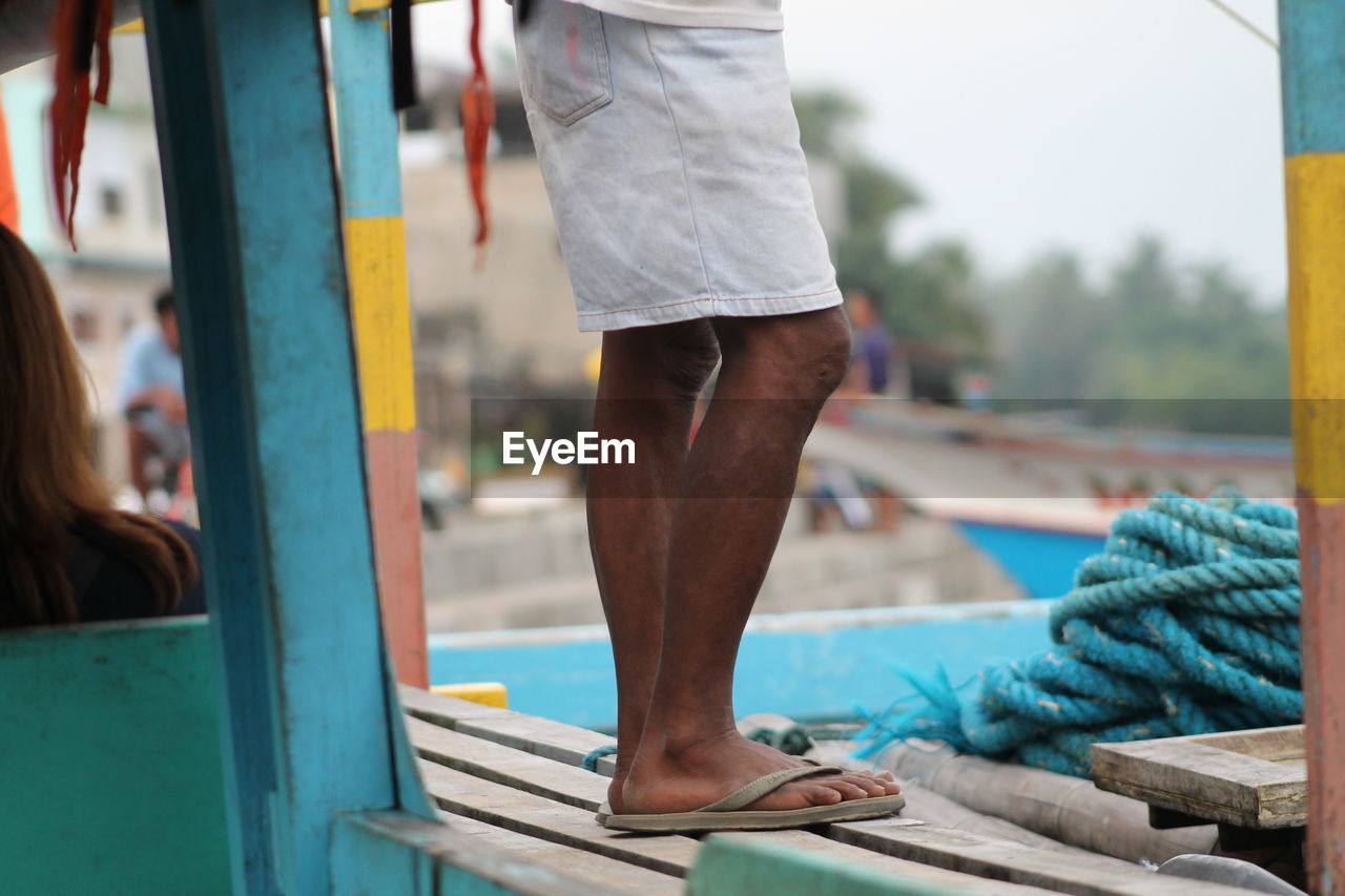 CLOSE-UP OF WOMAN STANDING ON RAILING