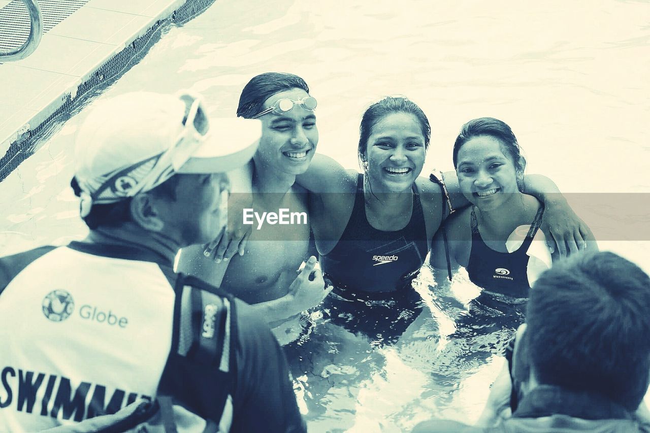 PORTRAIT OF SMILING YOUNG WOMAN SWIMMING POOL