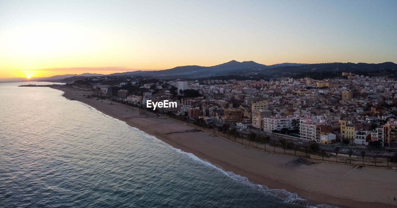 BUILDINGS BY SEA AGAINST SKY DURING SUNSET