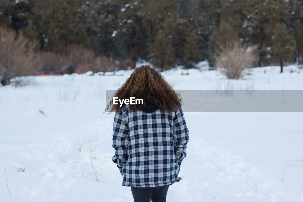 Rear view of woman walking on snow field