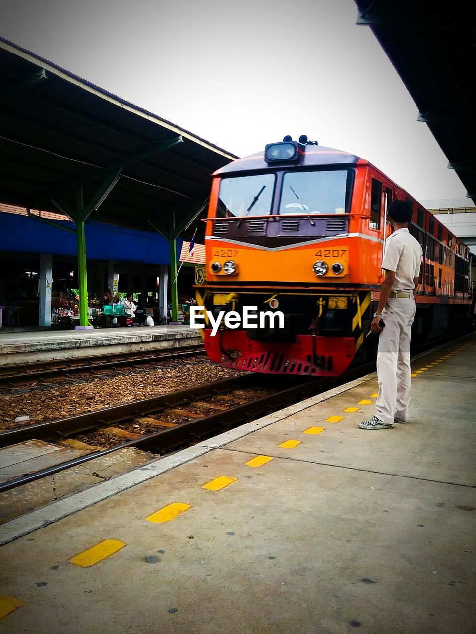 Train engineer standing by train at railroad station platform