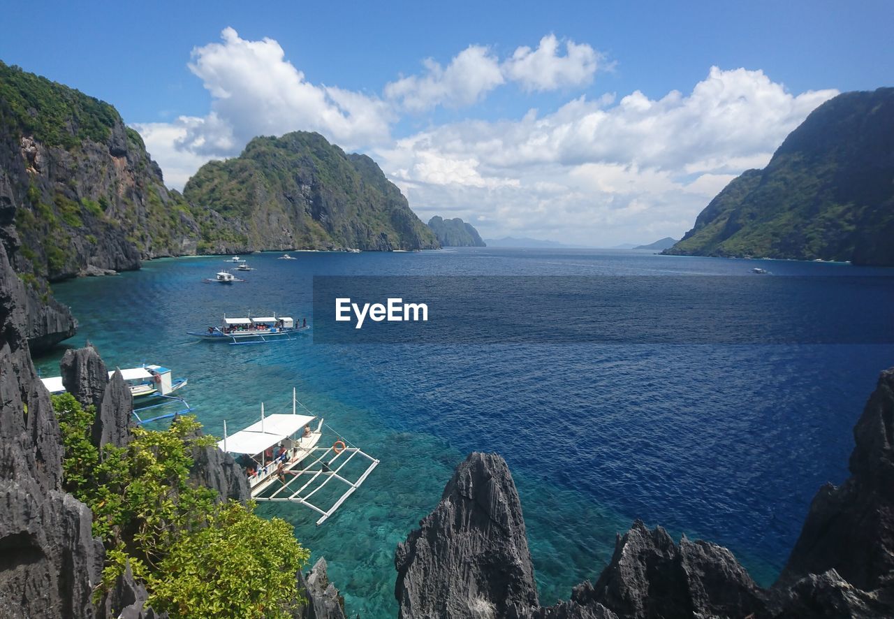 Scenic view of sea by mountains against sky