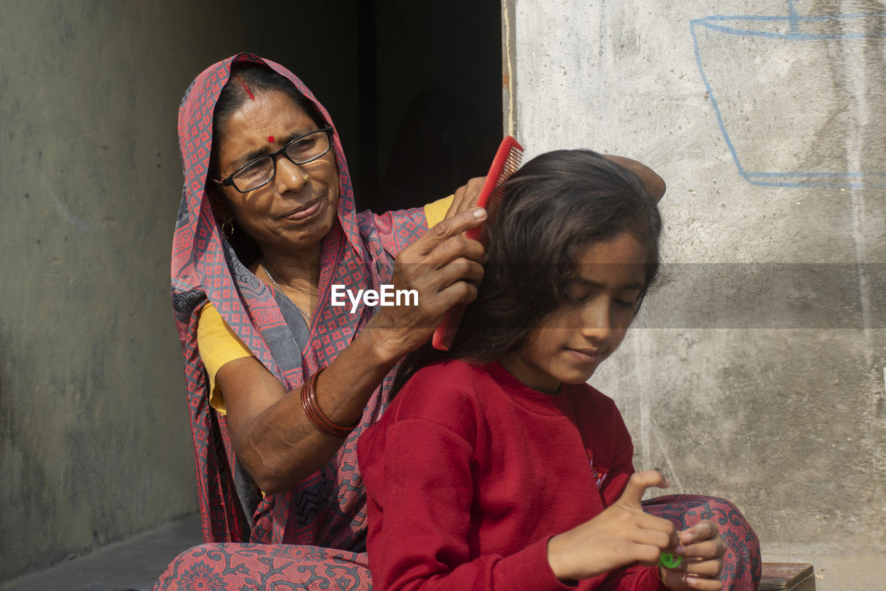 Woman combing daughter hair at home